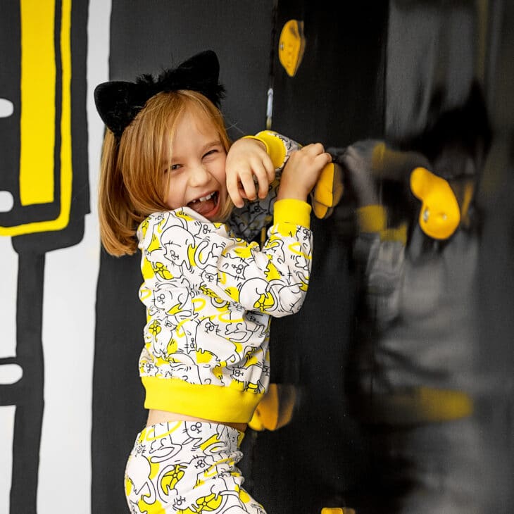 Dziewczynka w piżamce żółto-czarno-białej w kotki, żółty ściągacz, kocie uszka