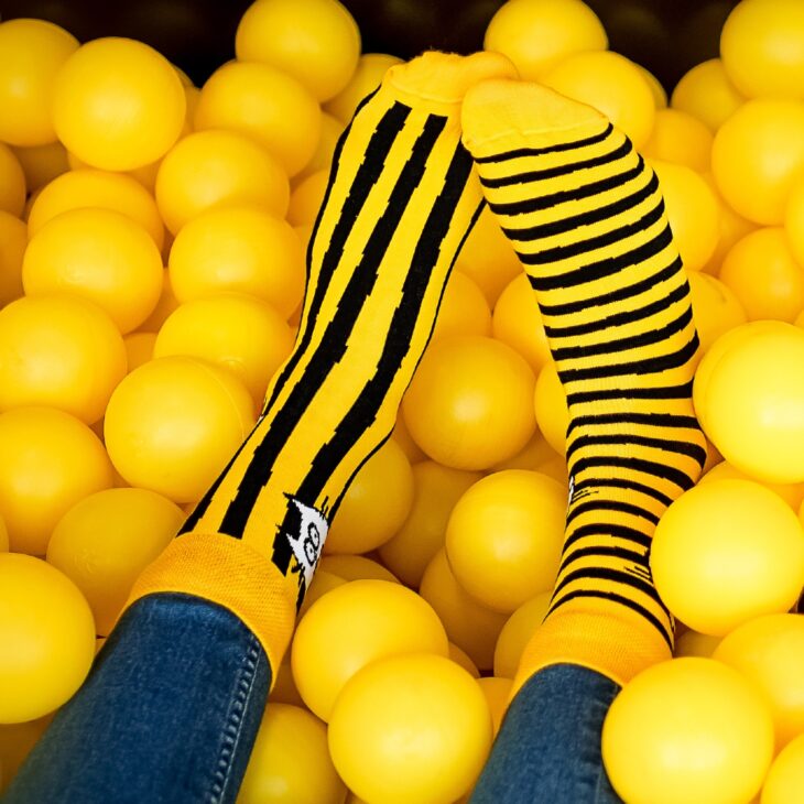 Skarpetki dwie różne, nie do pary, w paski pionowe i poziome żółto czarne widok na stopie
