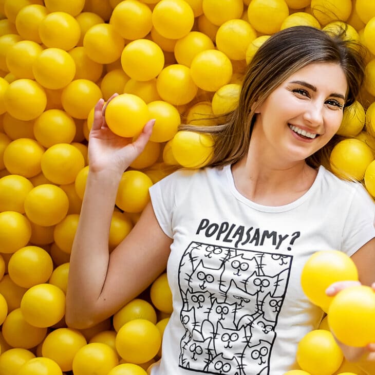 Dziewczyna w piłkach żółtych w stroju marki Dzikie Pląsy, t-shirt biały kot na kocie, radość, uśmiech