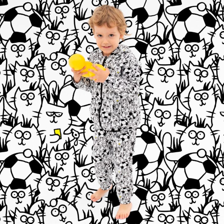 Chłopiec w stroju kotki na murawie dresy w koty czarno białe